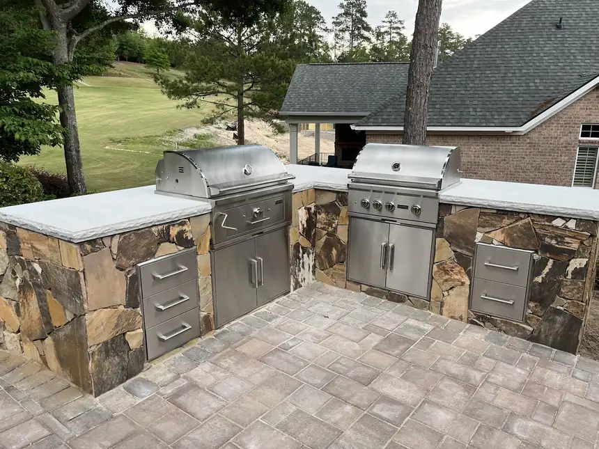 Flagstone-clad outdoor kitchen with two stainless grills, drawers and a paver floor