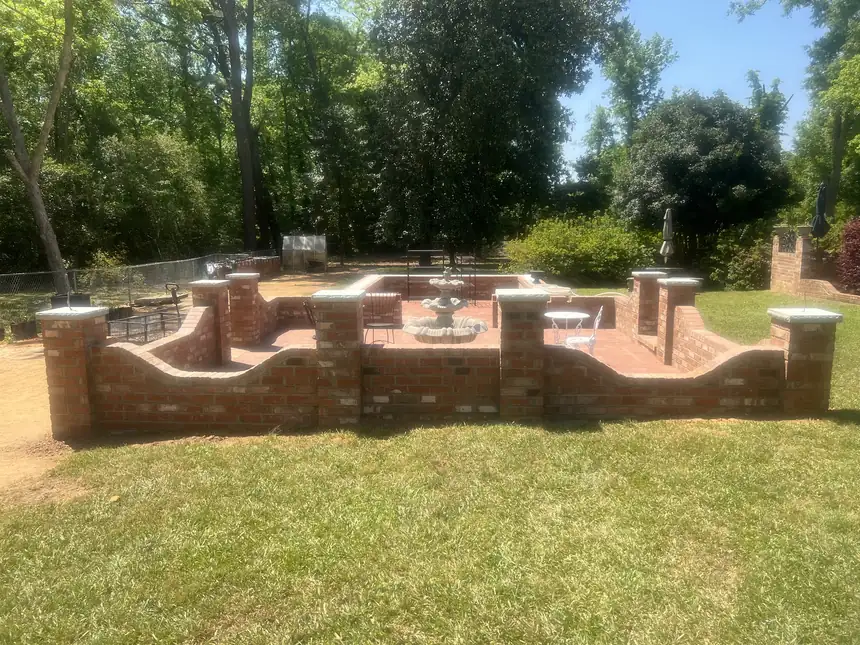 Curved brick garden wall with capped piers enclosing a brick patio and fountain